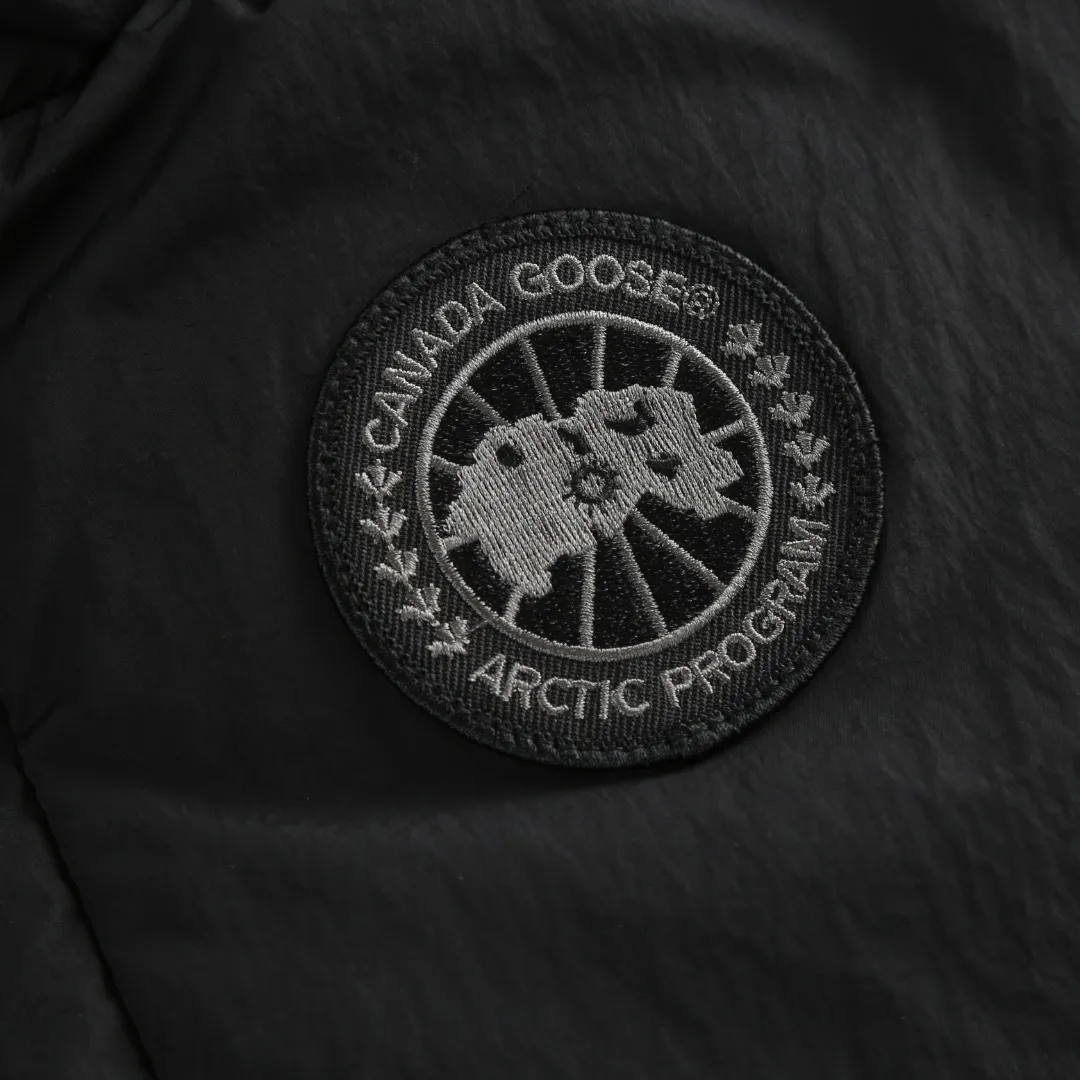 P740 Big Goose Logo Hooded Down Vest Fabric selection: The use of high-quality protective nylon fabric not only enhances the wear resistance of the surface, but also takes into account wind resistance, ensuring excellent performance in various harsh weather conditions.  90 national standard high-quality white duck down: selected high-loft down, weighing 170g, light and warm, with excellent temperature locking performance and good resilience.  Three-dimensional quilting process: Precision thread reinforcement to prevent velvet drilling and ensure that the fluffy and resilient elasticity lasts as new.  Details: Use polyester as the base for woven webbing, and use high-precision computer embroidery to decorate the brand letters on the webbing. The edges of the pattern are clear, the stitches are fine and even, and multiple layers of embroidery threads are stacked to enhance the three-dimensional effect. Accessories: One-to-one customized logo One-to-one customized zipper pendant One-to-one customized hem elastic buckle One-to-one customized snap button SIZE: S M L XL